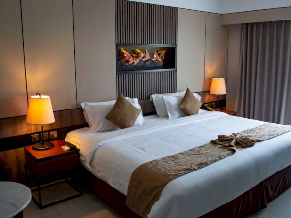 A neatly arranged hotel room with a large bed, decorative pillows, bedside lamps, and a stylish wall feature.