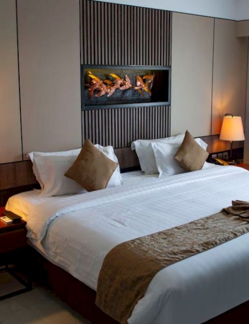 A neatly arranged hotel room with a large bed, soft lighting, and decorative pillows.