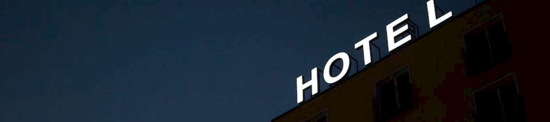 A building with a lit "HOTEL" sign on top against a dark night sky.