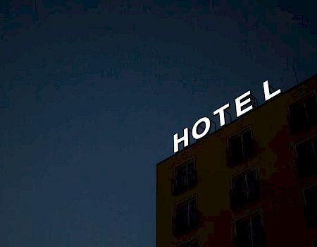 A building with a lit "HOTEL" sign on top against a dark night sky.