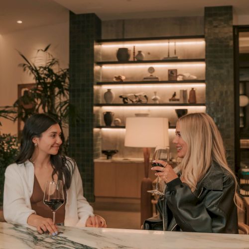 An espresso machine is brewing coffee into a clear glass cup, with crema forming on top, in a warm, softly lit setting.