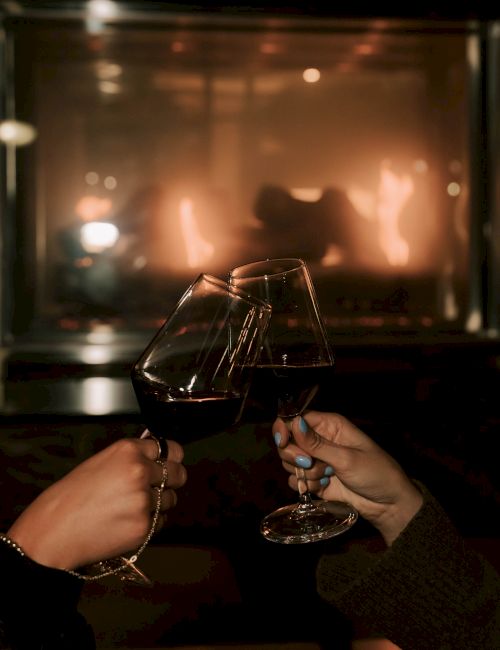 A plate of sliced tomatoes with mozzarella and basil, accompanied by a glass of red wine and a bottle on a marble surface.