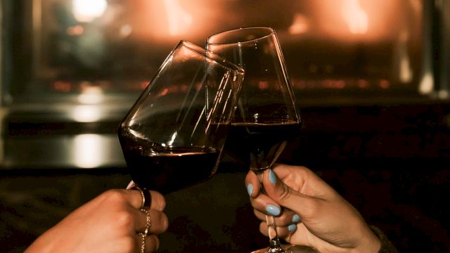 A woman smiles while playing guitar and singing into a microphone, surrounded by glowing lights and a lively atmosphere.