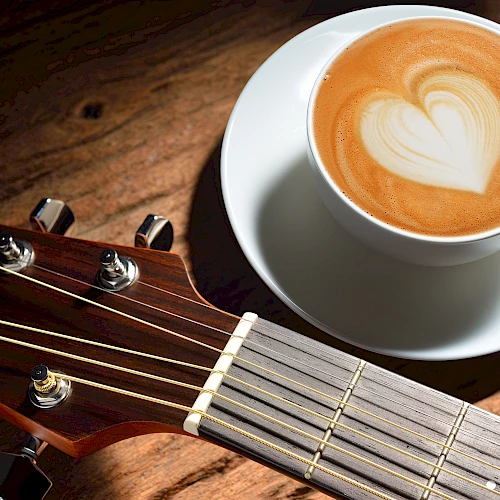 A musician in a hat plays an electric guitar on stage with bright lights and a lively atmosphere, creating a vibrant performance scene.