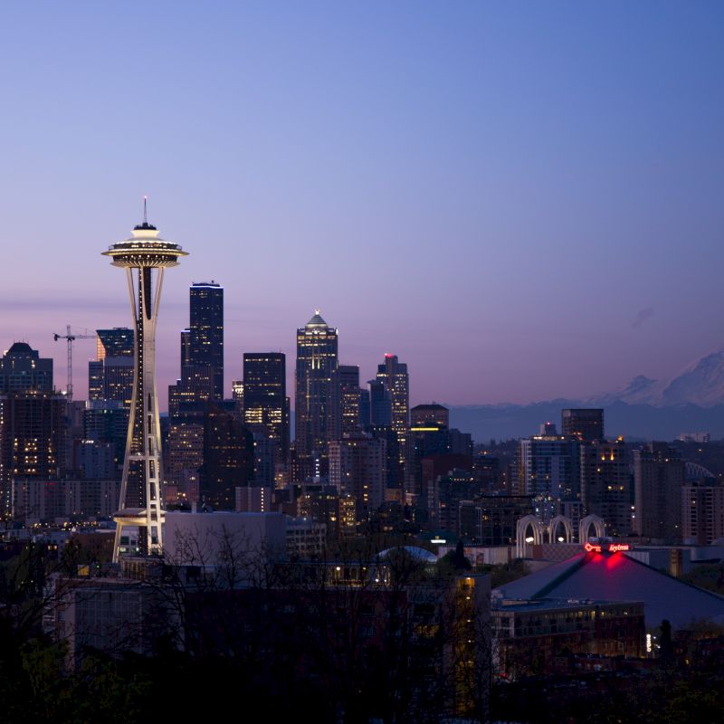 Seattle skyline at dusk with the Space Needle and Mount Rainier visible in the background.